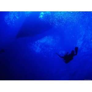One Man Scuba Diving Underwater in Blue Water near Boat and Surface 